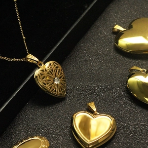 Macro view of gold heart locket with hollow filigree design and zircon stone details