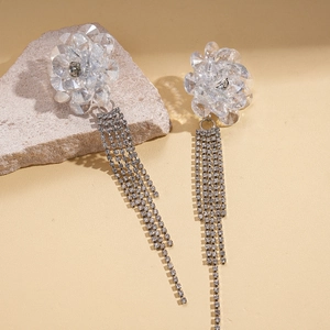 Detail of crystal flower tassel earrings with rhinestone fringe on beige stone
