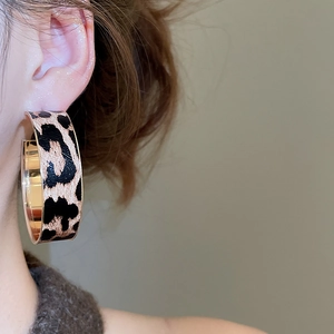 Close-up of vintage leopard print C-hoop earrings with gold-toned metal edging on a model