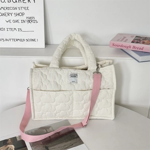 Detail of soft cream quilted handbag with CLOUD HUGGER woven label and pink shoulder strap