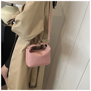Macro shot of pink geometric textured pillow bag with gold hardware on beige trench coat