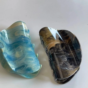 Detailed view of two marble patterned hair claw clips in blue-white and dark brown resin
