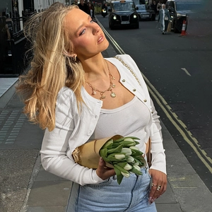 Détail de bijoux dorés élégants portés avec un gilet blanc boutonné et une tulipe