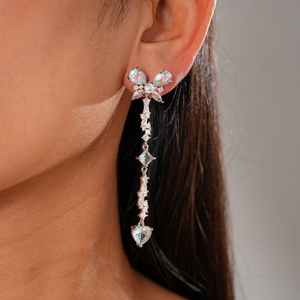 Detail view of long tassel butterfly earrings with light blue heart pendant on model