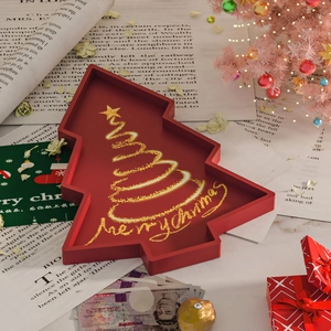 Detail view of red Christmas tree-shaped tray with gold Merry Christmas lettering