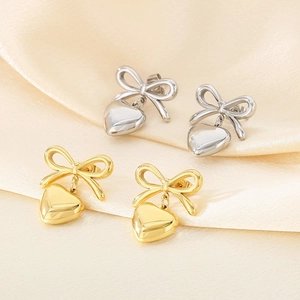 Detail of bow and heart earrings in gold and silver finish on soft silk fabric