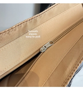 Detail shot of smooth silver metal zipper and durable inner lining of the woven straw bag