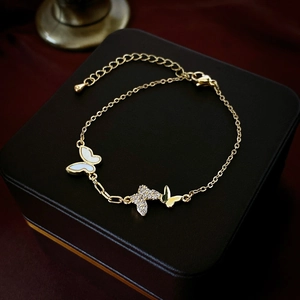 Détail d'un bracelet papillon doré avec incrustations de nacre et zircon sur boîte velours