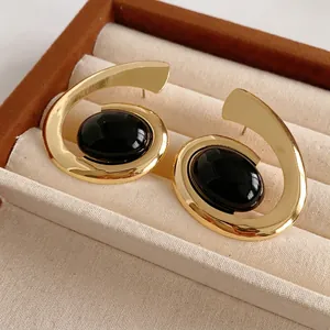 Retro golden spiral earrings with oval black stones displayed in a jewelry box
