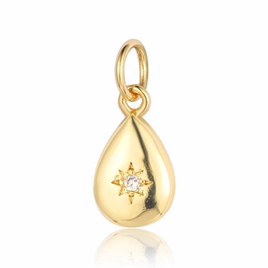 Macro shot of gold teardrop pendant with an eight-pointed star and sparkling clear zircon