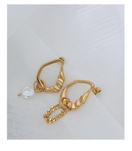 Detail of asymmetrical titanium earrings with faux pearl, gold plating and chain link