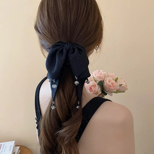 Detail of black glitter bow hair claw clip with crystal bead pendants on a low ponytail