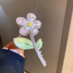 Détail d'une pince à cheveux fleur avec pétales en émail rose et strass scintillants