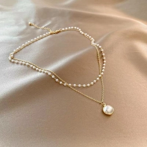 Detail of double-layer pearl necklace on champagne silk with elegant golden chain and clasp