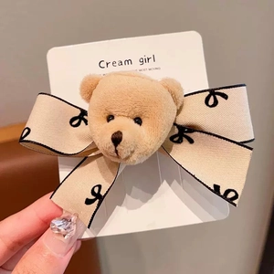 Detail of plush bear hair clip with beige ribbon bow and Cream Girl typography