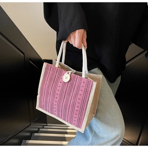 Detail of pink striped linen tote bag featuring a white button and rope handles