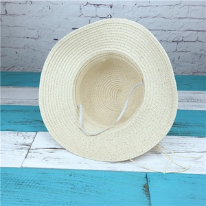 Detail of cream straw sun hat showing dense weave texture and white elastic wind strap