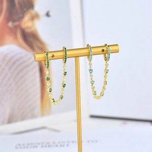 Elegant gold drop earrings with colorful zircon crystals on a stylish display stand