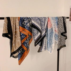 Detail of five silk-like scarves featuring paisley and floral prints on a rack