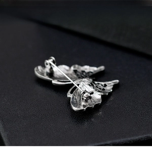 Macro shot of silver butterfly brooch back showing sturdy pin clasp and metal texture