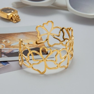 Detailed view of hollow floral 18k gold plated stainless steel open bangle with clover pattern