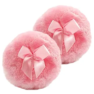 Set of two soft pink plush baby powder puffs with satin bows on a clean white background