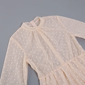 Detail of apricot mesh dress featuring mock neck, puff sleeves and delicate polka dot texture