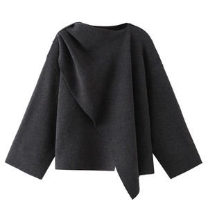 Detail of dark grey knitted poncho with asymmetric draped pleats and long sleeves texture