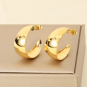 Macro shot of thick gold C-shaped stainless steel earrings on a jewelry box display