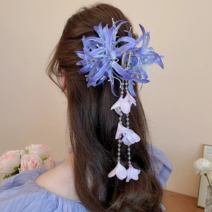 Détail d'une pince à cheveux lys en tissu violet avec de longs glands perlés élégants