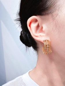 Close-up of vintage gold hollow lace C-shaped earrings with inlaid zircon on model