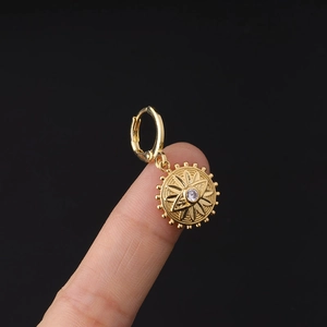 Macro view of a gold bohemian sunburst earring with a clear zircon stone on a finger