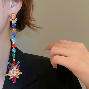 Close-up of model wearing multicolor teardrop crystal drop earrings with starburst design