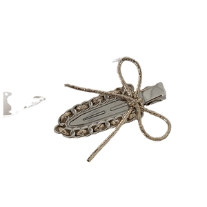 Silver metal bow hair clip with fabric ribbon and chain detail on white background