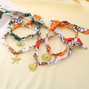 Détail de foulards en soie colorés avec pendentifs dorés en forme d'étoile de mer et coquillage