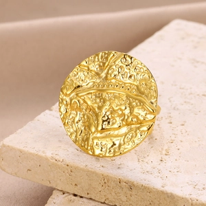 Macro shot of gold geometric ring with hammered texture on natural stone background