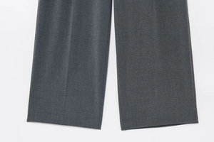 Détail du pantalon de costume gris foncé à jambes larges montrant le tissu texturé