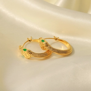 Gold snake earrings with green gem eyes on silk fabric, minimalist stainless steel jewelry
