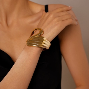 Detailed close-up of a large gold asymmetric geometric cuff bracelet worn by a model