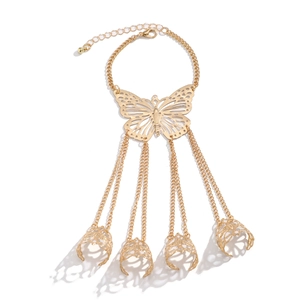 Macro del bracciale a mano con farfalla dorata e quattro anelli cavi su sfondo bianco