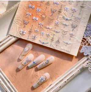 Detailed macro view of M-943 elegant gold foil nail stickers with blue bow and butterfly motifs