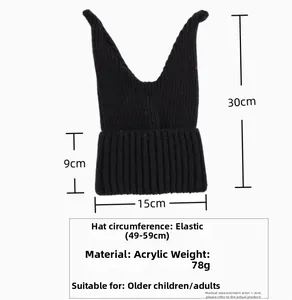 Detail of black ribbed knit winter hat with cat ear design and acrylic texture
