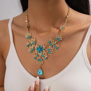 Detail of floral necklace with sky blue gemstones and a teardrop pendant on a model