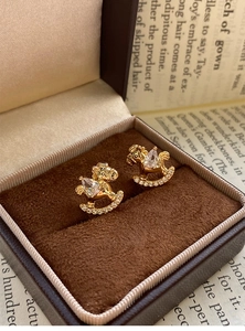 Macro shot of gold-plated rocking horse earrings with cubic zirconia in a velvet box
