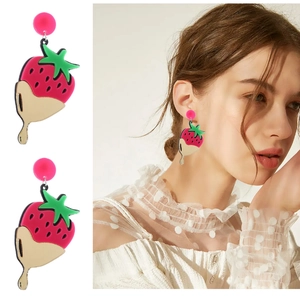 Detail view of strawberry chocolate acrylic earrings with pink studs on a model