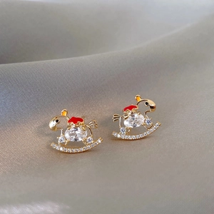 Detail of golden horse earrings with red enamel and crystals on gray silk fabric