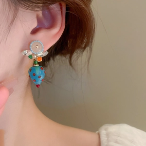 Detail of a model wearing a blue strawberry-shaped drop earring with red polka dots