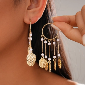Detail of bohemian gold tassel earrings featuring pink beads and hammered metal texture