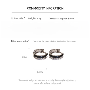 Detailed view of silver hoop earrings with zircon stones and black enamel inlay