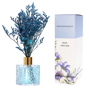 Blue reed diffuser set with blue dried flowers and a square glass bottle in white background
